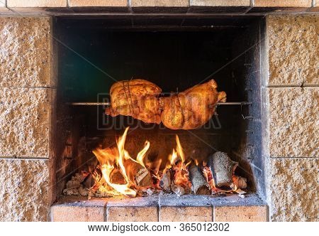 Chicken Roasting On A Spit In Garden Grill With Open Fire