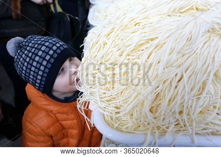 Child Eating Chechil Cheese In Market, Russia