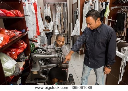 Small Business Owners Of Local Dry Cleaning Franchise Advising Staff About Clothing Repair