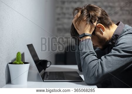Portrait Of Frustrated Young Businessman Holding Hands On His Head, Sitting Near Work Desk With Lapt