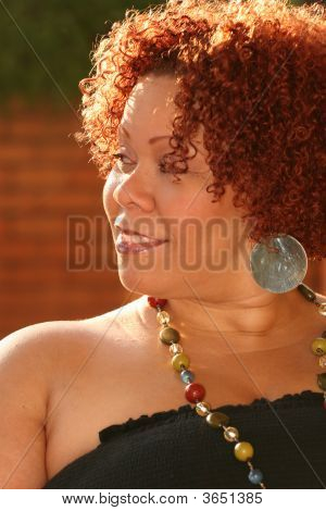 Mujer con cabello rizado rojo y joyas brillantes