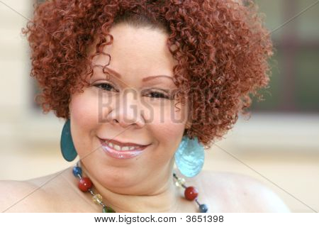 Mujer con cabello rizado rojo y joyas brillantes