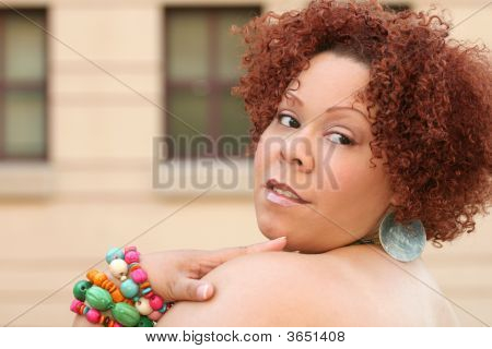 Mujer con cabello rizado rojo y joyas brillantes