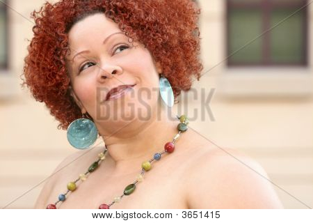 Mujer con cabello rizado rojo y joyas brillantes