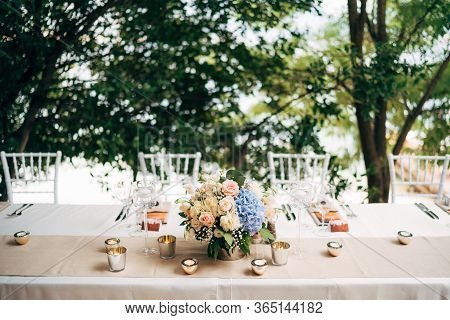 Wedding Dinner Table Reception. A Bouquet Of Pink Roses And Blue Hydrangeas Is On The Table In A Vas