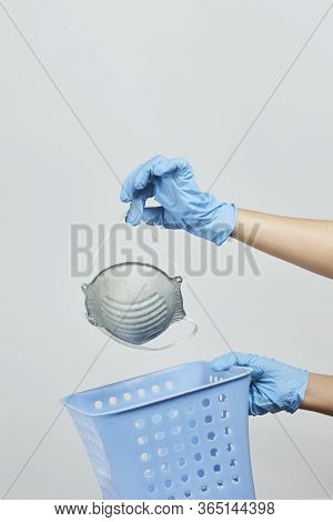 Female Hand Throwing A Personal Protective Face Mask To Rubbish Bin. Symbol Of The End Of Covid-19 Q