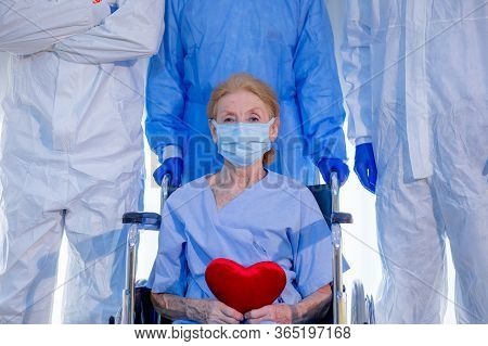 Old Woman Patient Hold Mini Heart On A Wheelchair With Background Of The Medical Team Thumbs Up Afte