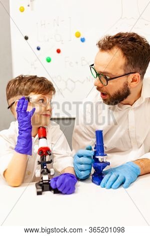Dad And Son Play With A Microscope In A Makeshift Laboratory
