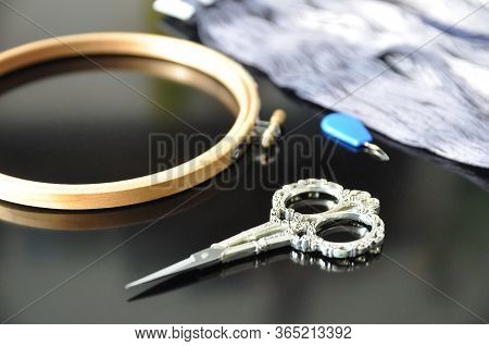 Accessories For Needlework. Hoop, Multi-colored Threads, Scissors, Needle-threader On A Black Backgr