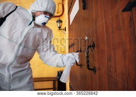 Coronavirus Pandemic. A Disinfector In A Protective Suit And Mask Sprays Disinfectants In House Or O
