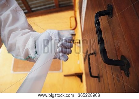 Coronavirus Pandemic. A Disinfector In A Protective Suit And Mask Sprays Disinfectants In House Or O