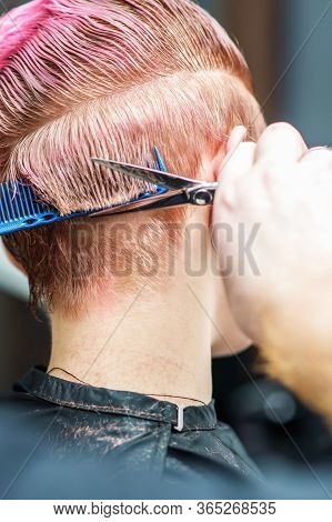 Close Up Of A Masculine Hand Is Cutting Hair With Scissors. Cutting Hair Close-up. Hairdresser Cuts 