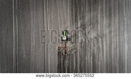 Aerial View Of A Clean Field In Which The Tractor Makes Vertical Tillage. Red Tillage Equipment And 
