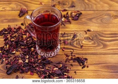 Glass Cup Of Red Hibiscus Tea (carcade, Roselle) On Wooden Table