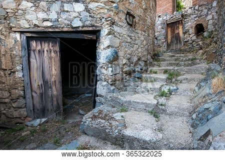 Stoned Step Road Leading To An Open Wooden Vintage Door At The Traditional Old Village Of Askas In C