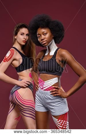 Kinesiology Taping. Two Young Female Athletes On Red Background With Kinesiology Tape On Neck, Shoul