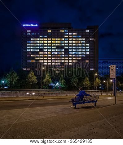 Man Sitting At A Bench Watching The Heart Shaped Illuminated Windows Of The Grand Westin Hotel In Mu