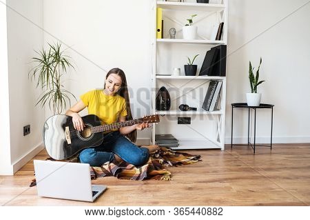 Online Training, Online Classes. A Young Woman Watches Video Tutorial On Guitar Playing, She Sits On