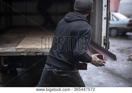 Loaders Are Loading Metal Into A Lorry. Transportation Of Heavy Industrial Products. Men Do Their Jo