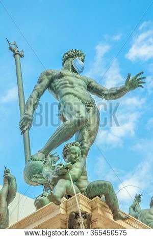 Close Up Of Statue Of Neptune With Surgical Mask, Symbol Of Bologna City During Covid-19 Time. Italy