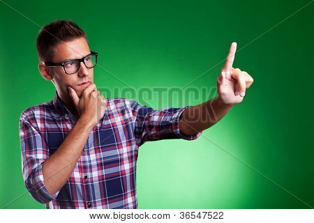 Giovane uomo casual citazioni selezionando qualcosa su uno schermo immaginario. Su sfondo verde