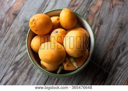 Ripe Medlar Fruit (eriobotrya Japonica) In Green Cup On Wooden Table. Top View.