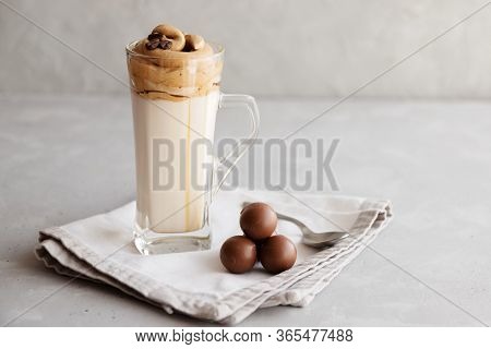 Cold Dalgon Milk And Coffee Drink In A Glass On A Linen Napkin And Next To Chocolates. Place For Tex