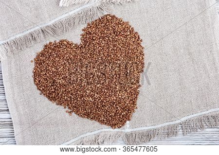 Raw Roasted Buckwheats In Shape Heart On Light Wood. Russian Grechka. Organic Healthy Diet Food.