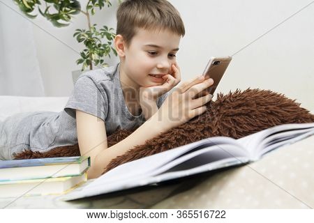 Schoolboy Boy With A Phone In His Hands. Communication Or Study With A Smartphone. Distance Learning
