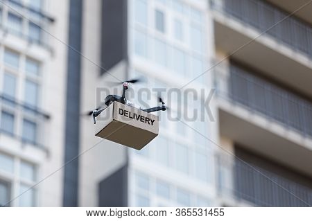 Drone For Air Delivery. Cardboard Package Shipment By Helicopter Drone Through The City While Quaran