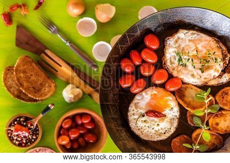 Fried Eggs In A Frying Pan With Cherry Tomatoes And Bread For Breakfast . Fried Potatoes And Tomatoe