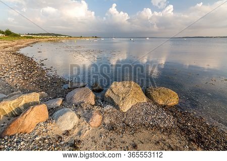 Scenic Beach With Rocks And Boats In The Background At The Baltic Sea During Sunrise