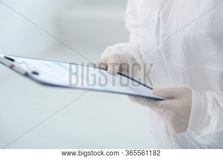 Close-up Of Medical Worker Hands In Gloves Holding Clip Folder