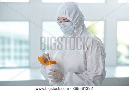 Medical Worker In Protective Clothing, Medical Mask And Goggles Holding Disinfecting Wipes Bottle, P