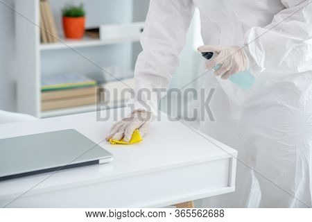 Close-up Of Medical Worker Hands In Gloves Spraying Disinfectant On Table