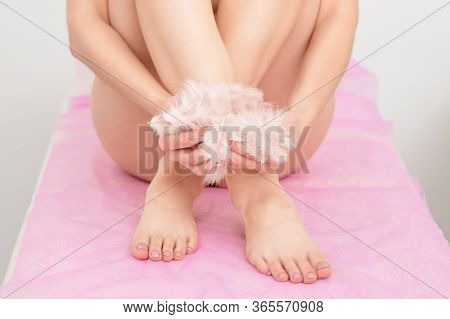 Woman Holding White Feathers In Her Arms Sitting And Hugging Her Smooth Legs.