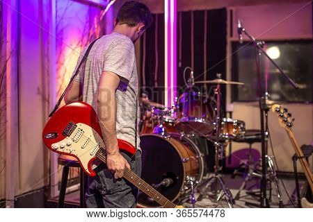 A Man Plays An Electric Guitar In A Recording Studio. A Rehearsal Room For Musicians With A Drum Kit