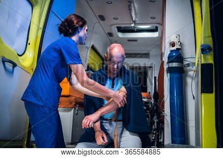 Young Nurse In A Uniform Wraps A Tourniquet Around The Patients Hand To Take A Blood Test