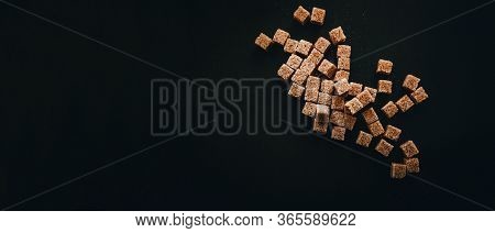 Brown Cane Sugar In Cubes On A Black Background. Still Life.