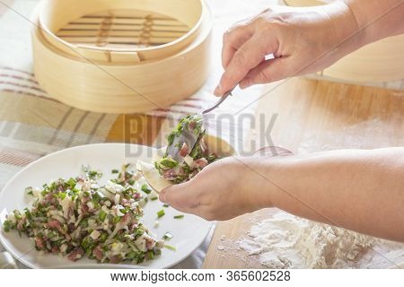 Female Hands Make Manti, Khinkali, Dumplings Or Wonton From Dough With Minced Meat Filling And Green