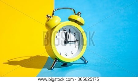 Yellow Vintage Alarm Clock On A Blue And Yellow Background With Selective Focus, Copy Space For Text