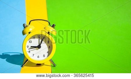 Yellow Vintage Alarm Clock On A Blue And Yellow And Green Background With Selective Focus, Copy Spac