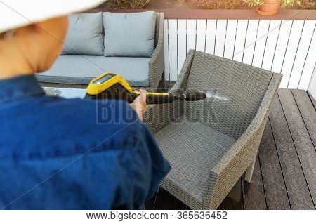Woman Doing Garden Terrace Furniture Cleaning With High Pressure Washer