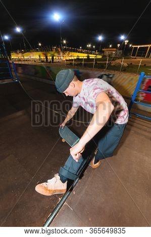 A Young Skatecrack In A Night Skatepark Does A Halfpipe Jump Jump. Youth Culture Leisure Concept At 