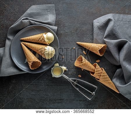 Vanilla Ice Cream Scoops, Scooped From Container In To Waffle Cones With A Silver Utensil