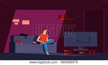 Single Man Sits In His Apartment On The Couch, Cross-legged, With A Remote Control In His Hand And W