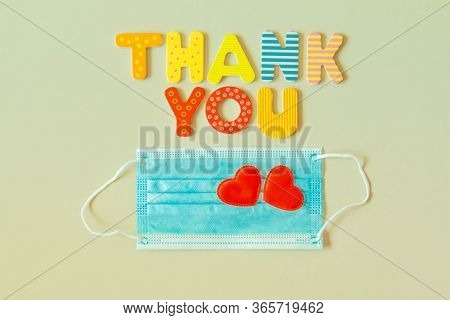 Heart Symbols On Disposable Medical Mask And Text Thank You Of Wood Letters. Words Thank You And Blu