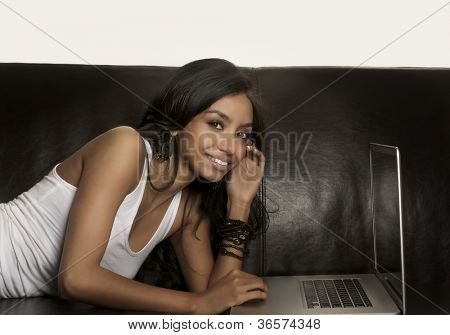 Junge Frau mit Laptop-Computer auf Sofa.
