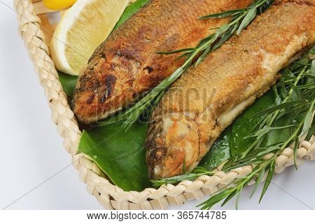 Grilled Fish In A Wicker Basket With Greens On A White Background. Isolate Creative Presentation And