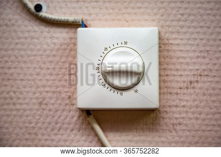 White Old Temperature Controller Switch With Wires On A Beige Wall. Horizontal Orientation.